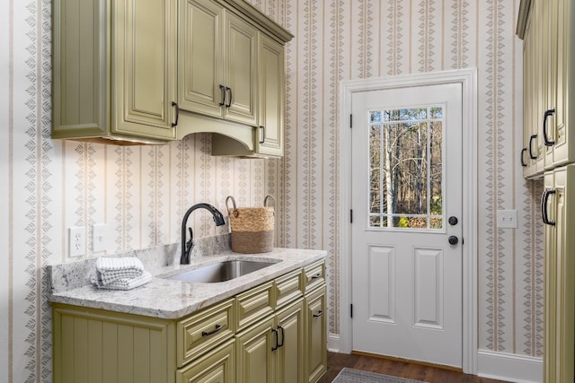 kitchen with light stone countertops, dark wood finished floors, a sink, and refrigerator