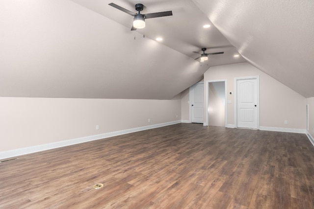 additional living space with lofted ceiling, ceiling fan, dark wood-type flooring, visible vents, and baseboards