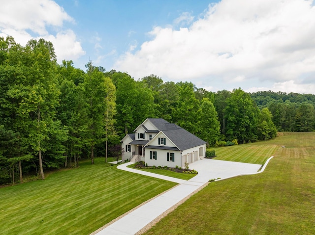 view of front of home with driveway, a front lawn, and a wooded view