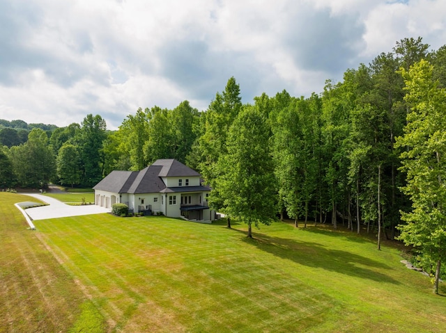 view of yard with a garage, driveway, and a wooded view