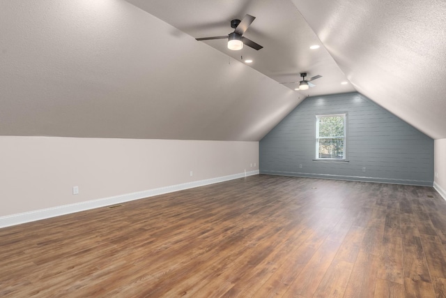 additional living space featuring a textured ceiling, baseboards, vaulted ceiling, and dark wood-type flooring