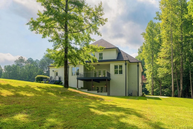 rear view of property featuring roof with shingles, a lawn, a ceiling fan, and stucco siding