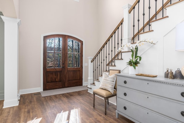 foyer entrance with dark wood-style floors, french doors, stairway, and decorative columns