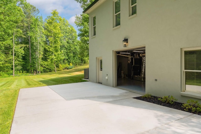 view of patio with concrete driveway, central AC, and an attached garage