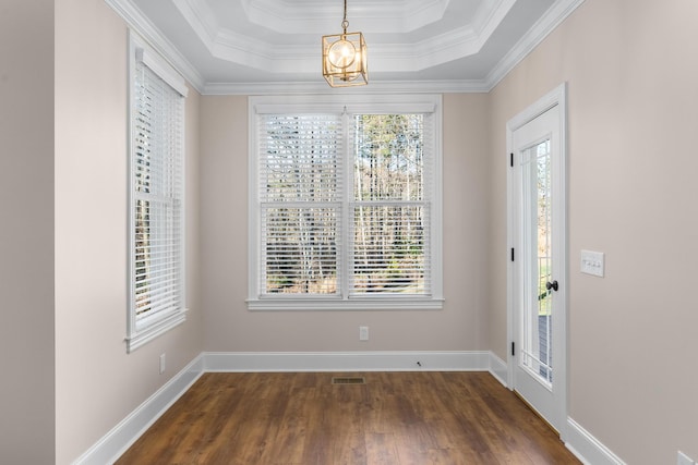 foyer entrance featuring a notable chandelier, dark wood-type flooring, baseboards, ornamental molding, and a raised ceiling