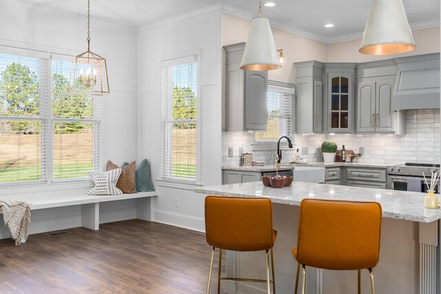 kitchen featuring stainless steel range with electric stovetop, glass insert cabinets, gray cabinets, and a kitchen breakfast bar