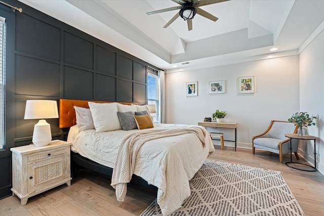 bedroom with baseboards, visible vents, a tray ceiling, light wood-type flooring, and recessed lighting