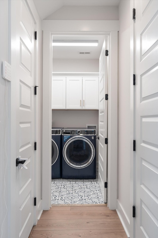 washroom featuring cabinet space, visible vents, light wood finished floors, and washer and dryer