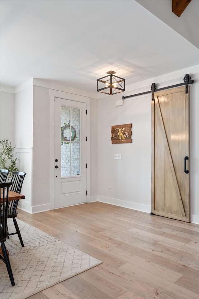 entrance foyer featuring baseboards, light wood finished floors, and a barn door