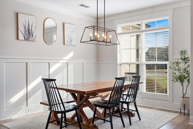 dining area featuring wainscoting, visible vents, an inviting chandelier, and wood finished floors