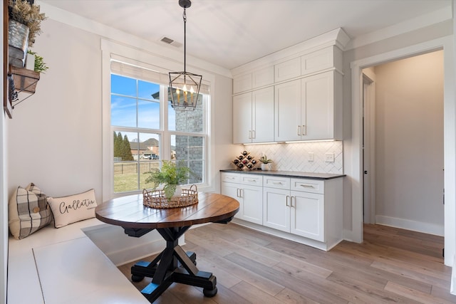 dining space with visible vents, baseboards, light wood finished floors, breakfast area, and an inviting chandelier