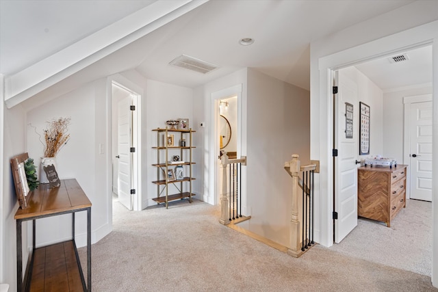 hallway with carpet, visible vents, and an upstairs landing