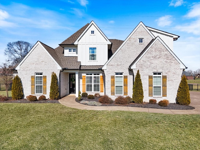 view of front of house with a front lawn, board and batten siding, a shingled roof, and brick siding