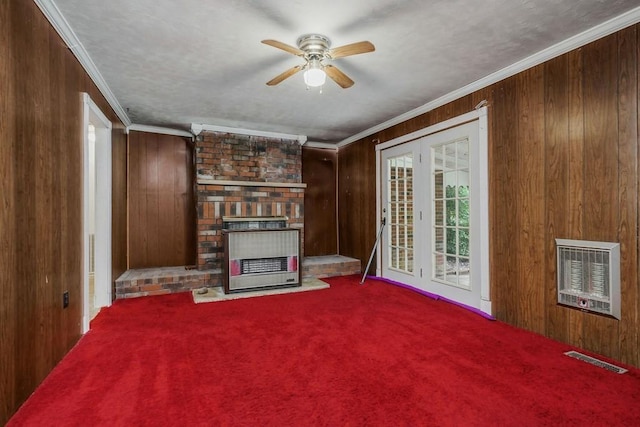 unfurnished living room featuring wooden walls, visible vents, a brick fireplace, heating unit, and crown molding