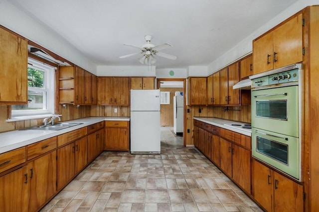 kitchen with white appliances, under cabinet range hood, light countertops, and brown cabinetry