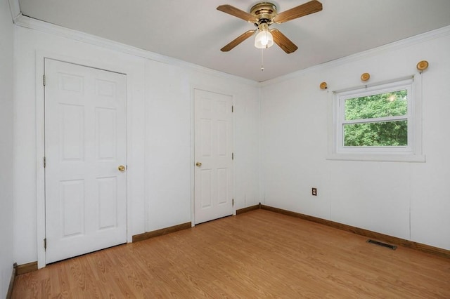 unfurnished bedroom featuring ceiling fan, visible vents, baseboards, light wood finished floors, and crown molding