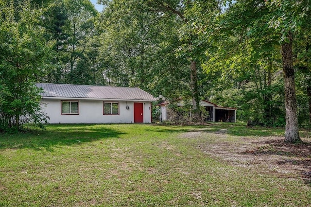 ranch-style home featuring a front yard, metal roof, driveway, and stucco siding