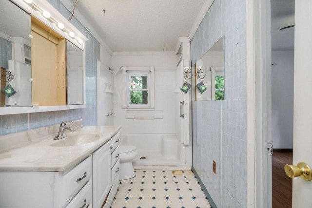 bathroom with toilet, vanity, tile walls, a shower stall, and crown molding