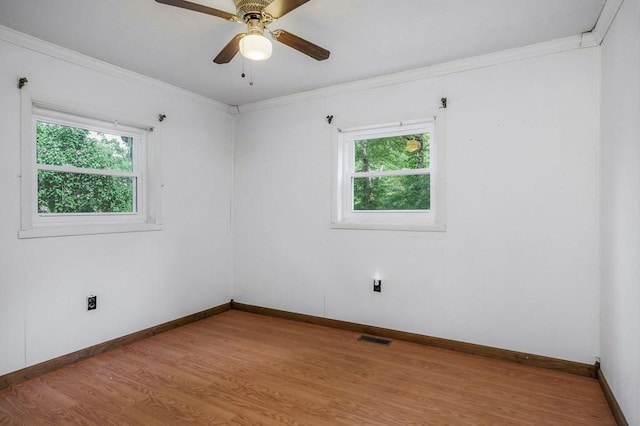 empty room with baseboards, light wood-type flooring, visible vents, and crown molding