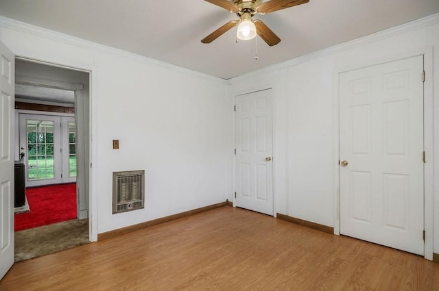 unfurnished bedroom featuring crown molding, light wood-style floors, baseboards, and heating unit