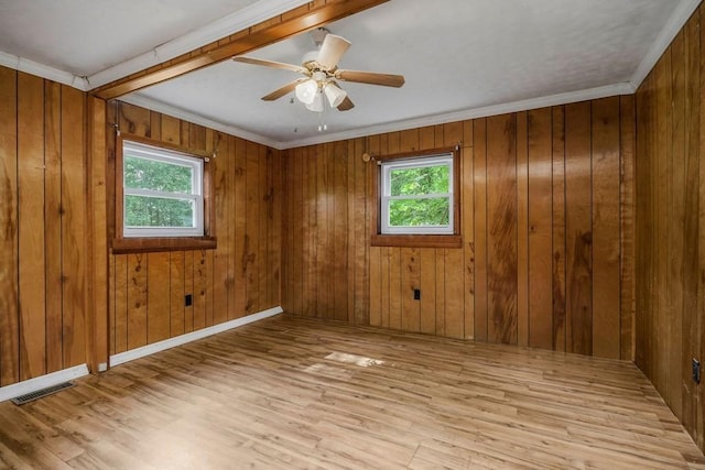 empty room with a healthy amount of sunlight, light wood-style flooring, wooden walls, and visible vents