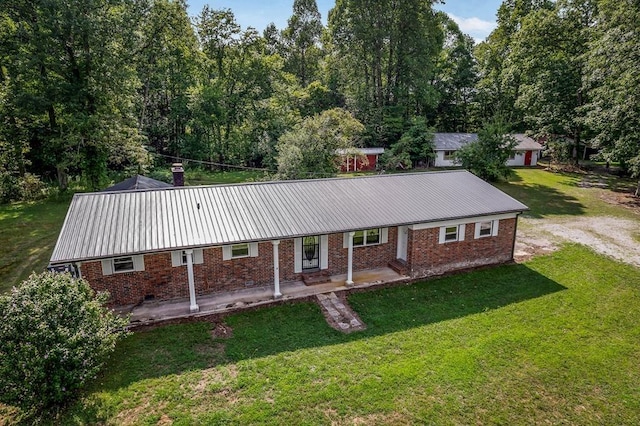 view of front of home with a porch, a front yard, brick siding, and metal roof