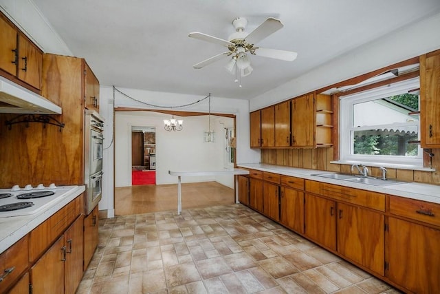 kitchen featuring a sink, light countertops, hanging light fixtures, brown cabinets, and open shelves