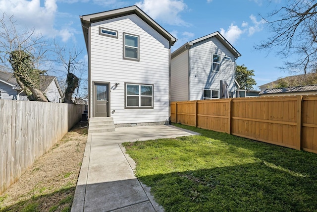 back of property with entry steps, a fenced backyard, a patio, and a yard