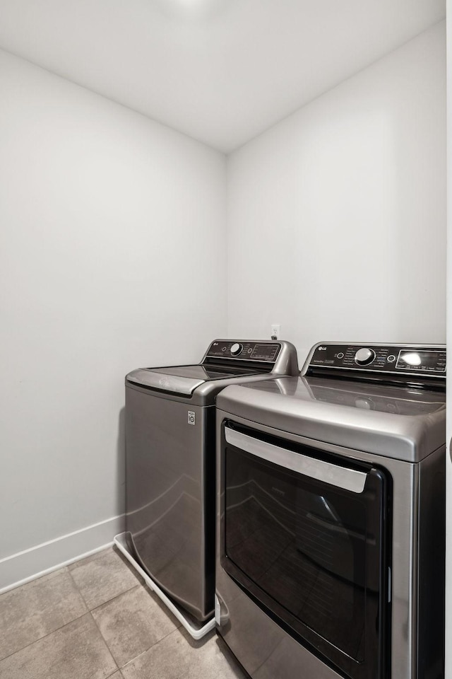 clothes washing area with laundry area, baseboards, and washer and clothes dryer