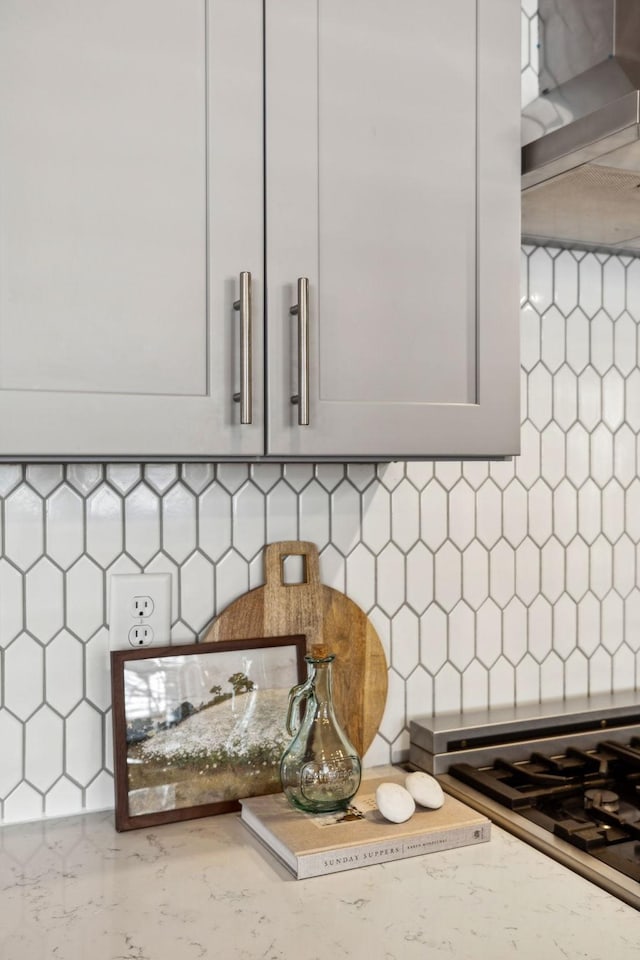 interior details with light stone counters, stainless steel gas stovetop, and decorative backsplash