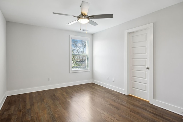 spare room featuring a ceiling fan, visible vents, dark wood finished floors, and baseboards