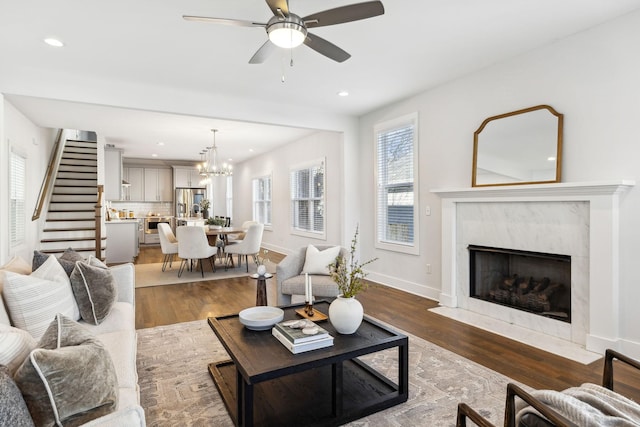 living room featuring a premium fireplace, baseboards, wood finished floors, and recessed lighting