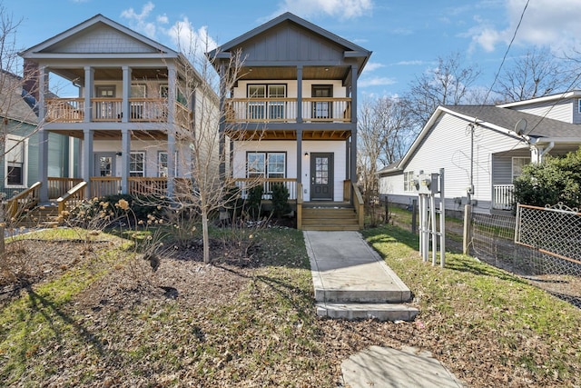 view of front of house featuring board and batten siding, covered porch, fence, and a balcony