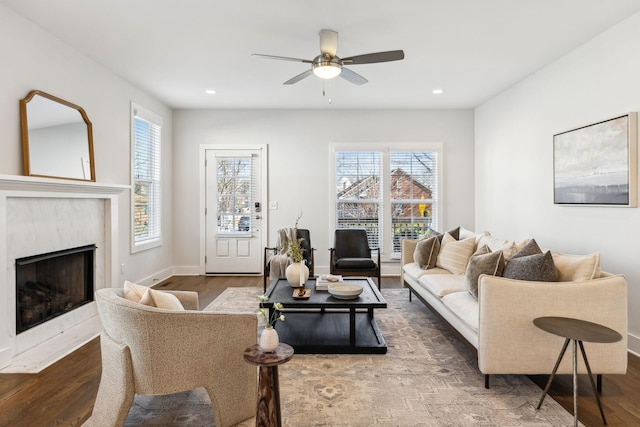 living room featuring a premium fireplace, baseboards, wood finished floors, and recessed lighting