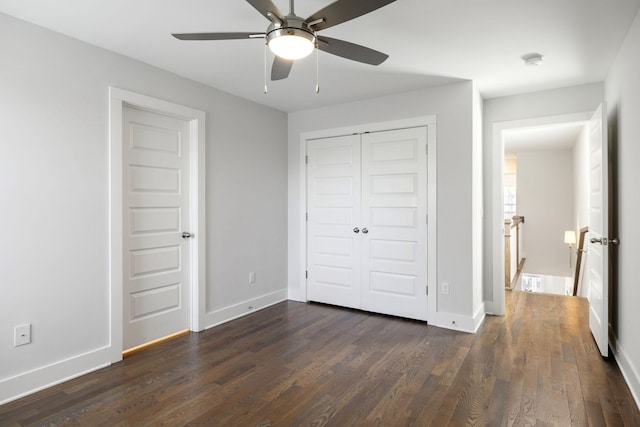 unfurnished bedroom with a closet, dark wood-style flooring, ceiling fan, and baseboards