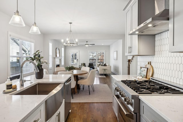 kitchen featuring wall chimney exhaust hood, stainless steel appliances, a wealth of natural light, and a lit fireplace