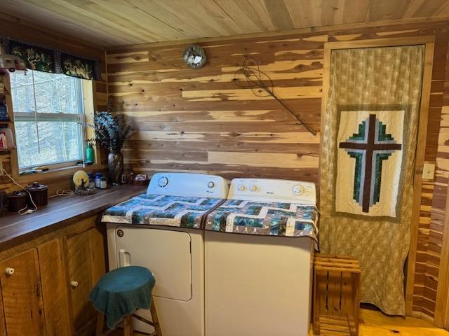 laundry area with wood ceiling, laundry area, washing machine and dryer, and wooden walls