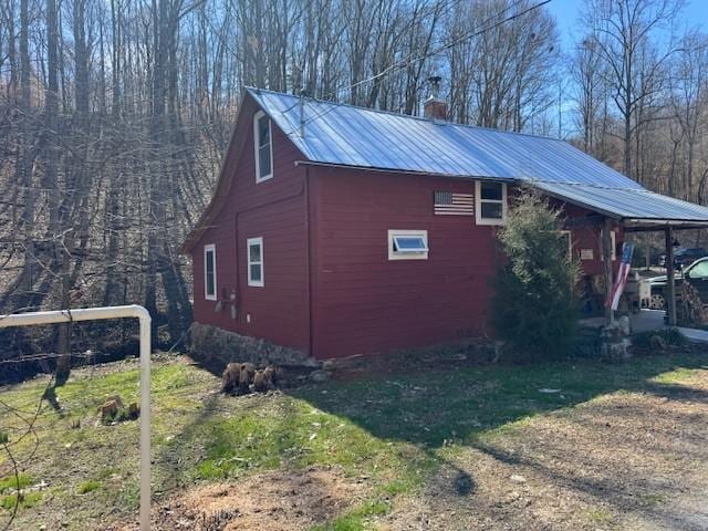 view of side of property with metal roof and a chimney