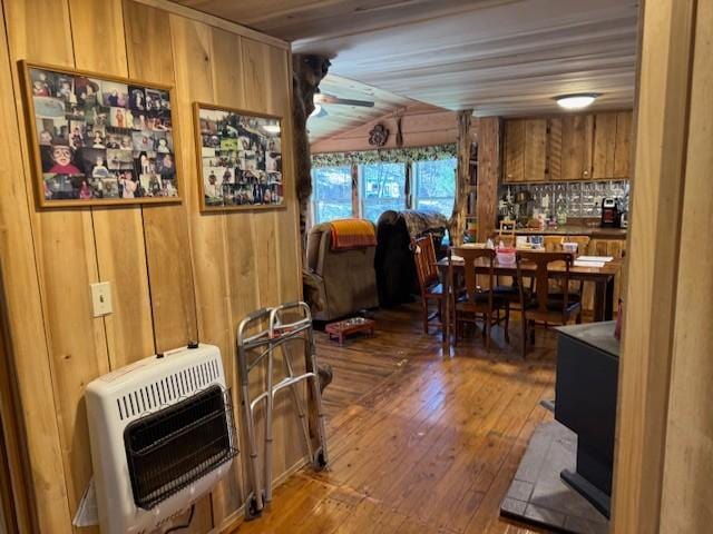 dining area featuring ceiling fan, wood walls, wood finished floors, and heating unit