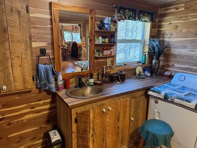 kitchen featuring brown cabinetry, plenty of natural light, a sink, and wood walls