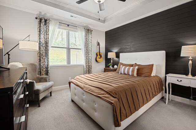 bedroom with visible vents, a tray ceiling, crown molding, and light colored carpet