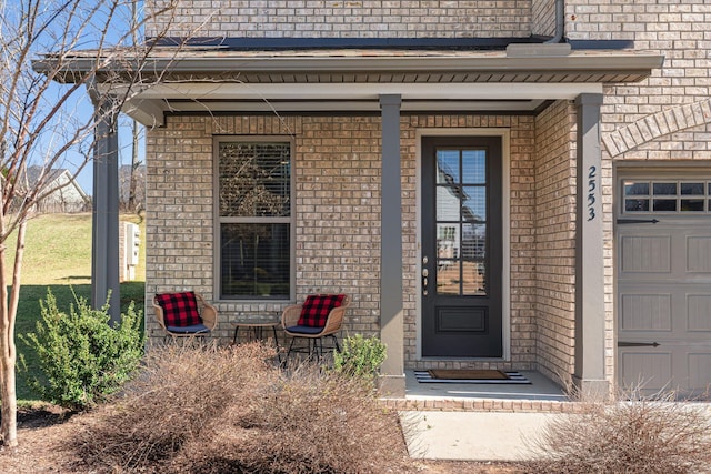 property entrance with an attached garage, a porch, and brick siding