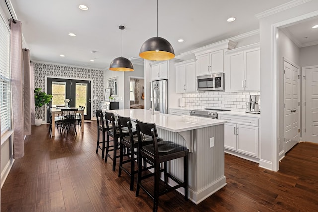 kitchen with stainless steel appliances, light countertops, a center island with sink, and white cabinetry