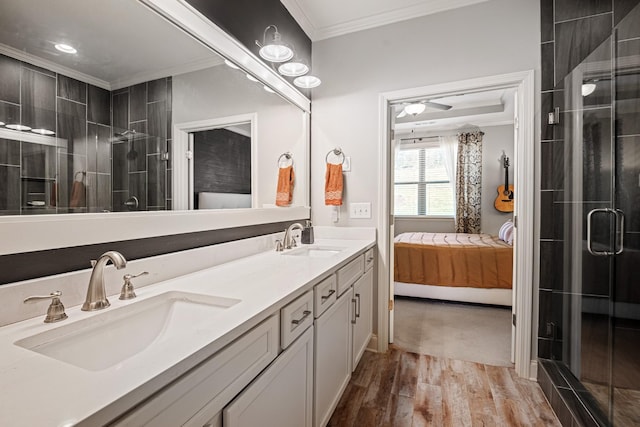 bathroom with connected bathroom, ornamental molding, a sink, and wood finished floors