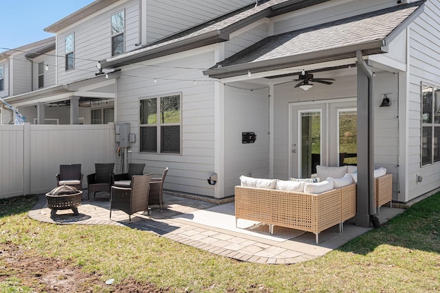 back of property with a shingled roof, an outdoor living space with a fire pit, ceiling fan, fence, and a patio area