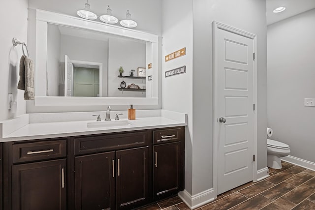 bathroom featuring toilet, baseboards, vanity, and wood tiled floor