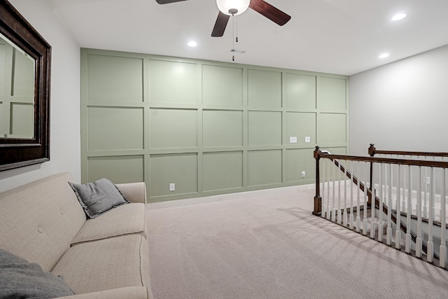 living area featuring ceiling fan, carpet flooring, an upstairs landing, a decorative wall, and recessed lighting