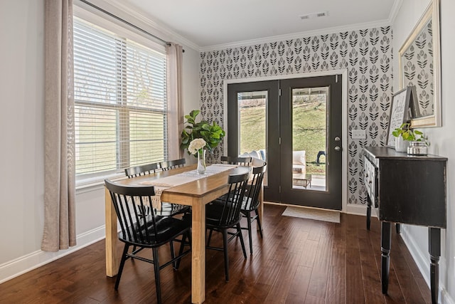 dining space featuring dark wood-style floors, visible vents, ornamental molding, baseboards, and wallpapered walls