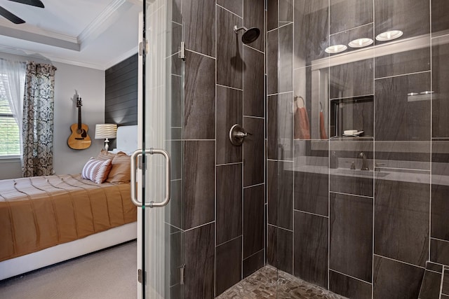 ensuite bathroom featuring ceiling fan, ensuite bath, a tray ceiling, a tile shower, and crown molding