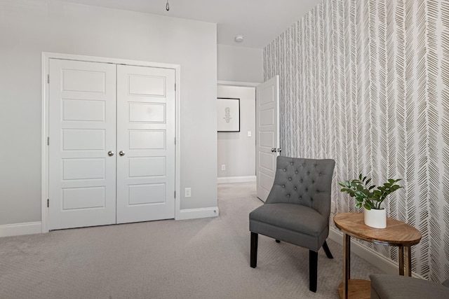 sitting room with baseboards and light colored carpet